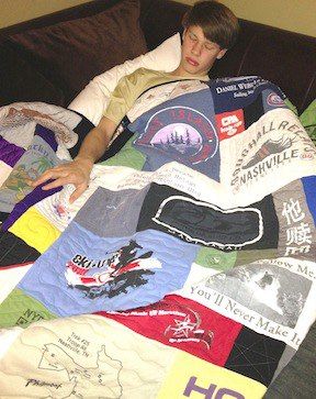 A young man sleeping under his T-shirt quilt by Too Cool T-shirt Quilts