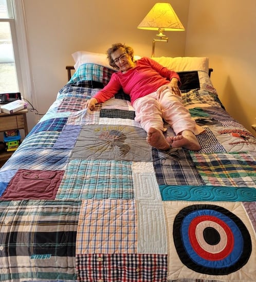 90 year old woman on hubands memory quilt made by Too Cool T-shirt Quilts