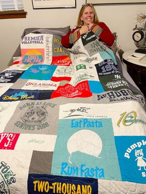 Woman under covers of a T-shirt quilt