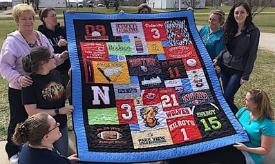 A gang of T-shirt quilt makers and their quilts at Too Cool T-shirt Quilts